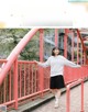 A woman standing on a red bridge with her arms outstretched.
