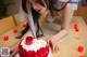 A woman in a wedding dress cutting a cake with candles.