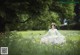 A woman in a white dress sitting in a field of flowers.