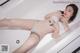 A woman laying in a bathtub with a tattoo on her chest.