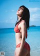 A woman in a red bikini standing on the beach.