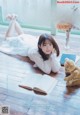 A woman laying on the floor next to a book and a teddy bear.