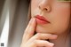 A close up of a woman's face with her hand on her chin.