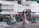 A woman in a pink dress standing in front of a building.