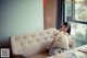 A woman sitting on a couch in front of a window.